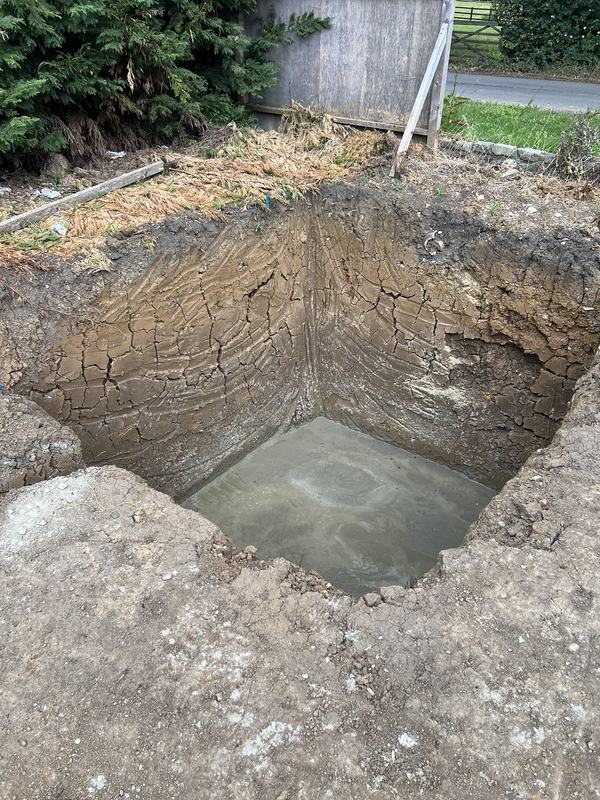 Deep square excavation pit with a freshly poured concrete base, ready for a sewage treatment plant