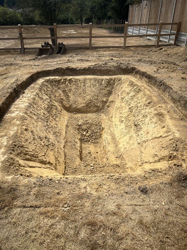Neatly excavated rectangular pit with sloped sides, dug ready for an in-ground trampoline
